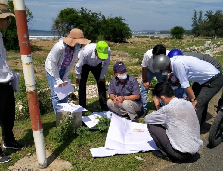 A group of people outside looking at papers

Description automatically generated